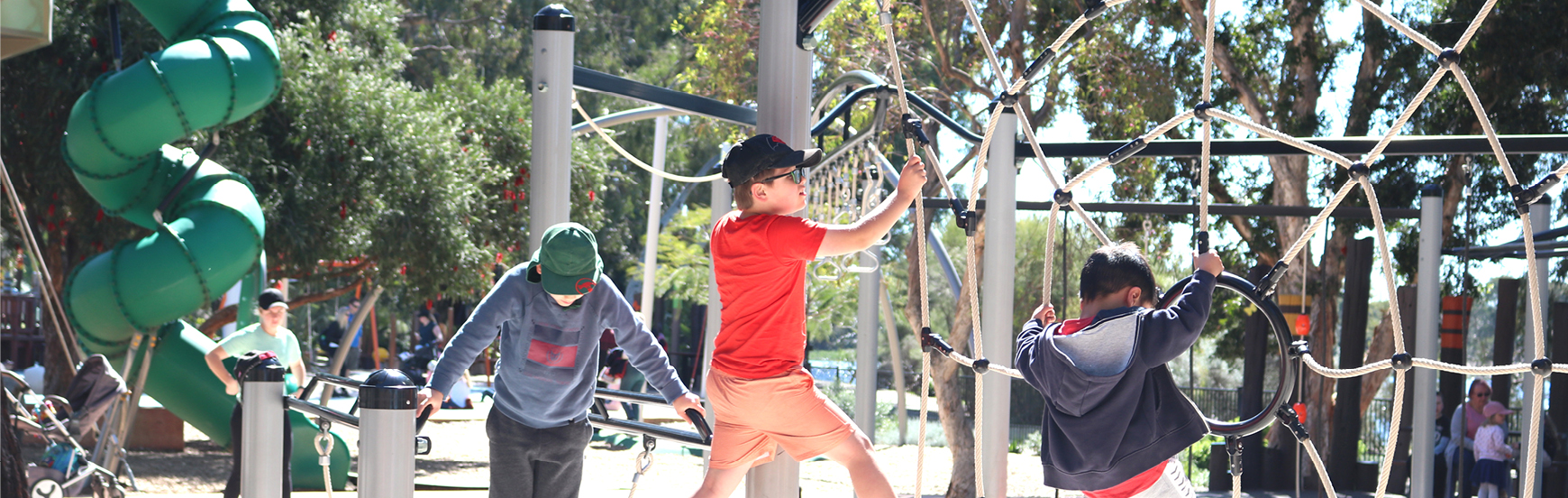 Children playing on a piece of equipment that looks like a spider web with a loopy slide in the background